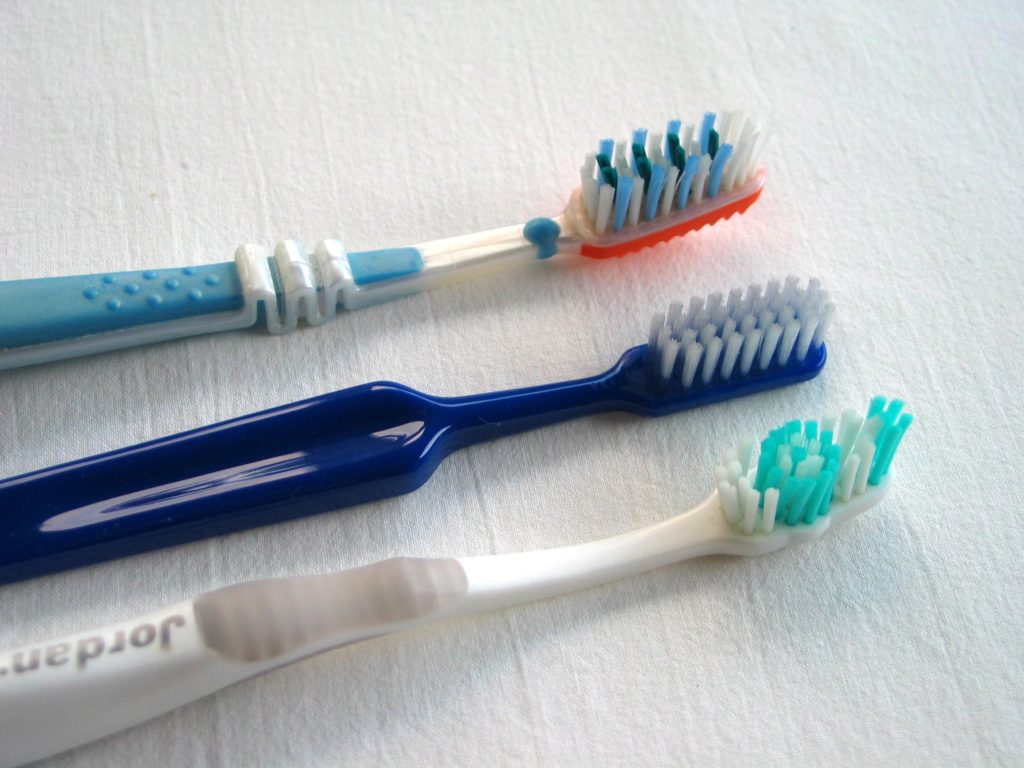 Three toothbrushes in a row with different brush types.